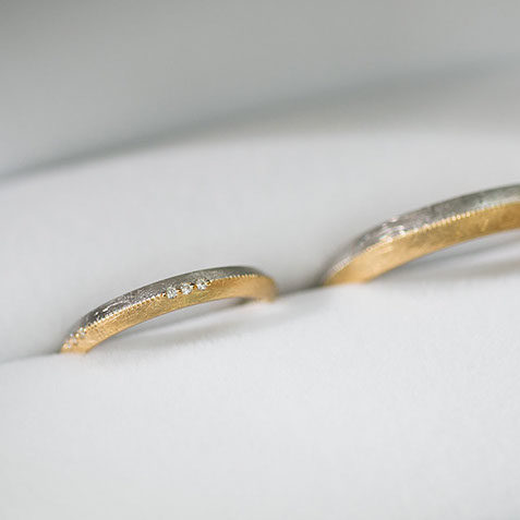コンビネーションの結婚指輪。プラチナ950とK18イエローゴールドを使用し、表面にはダイヤモンド加工を施しました。レディースアップ写真。