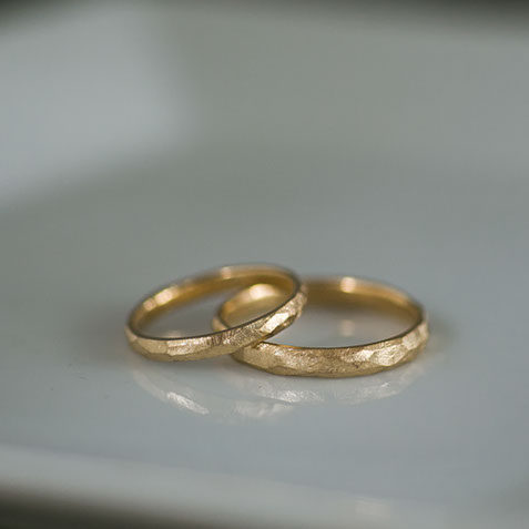 陶器の器に並べたK18イエローゴールドの結婚指輪のペアショット。